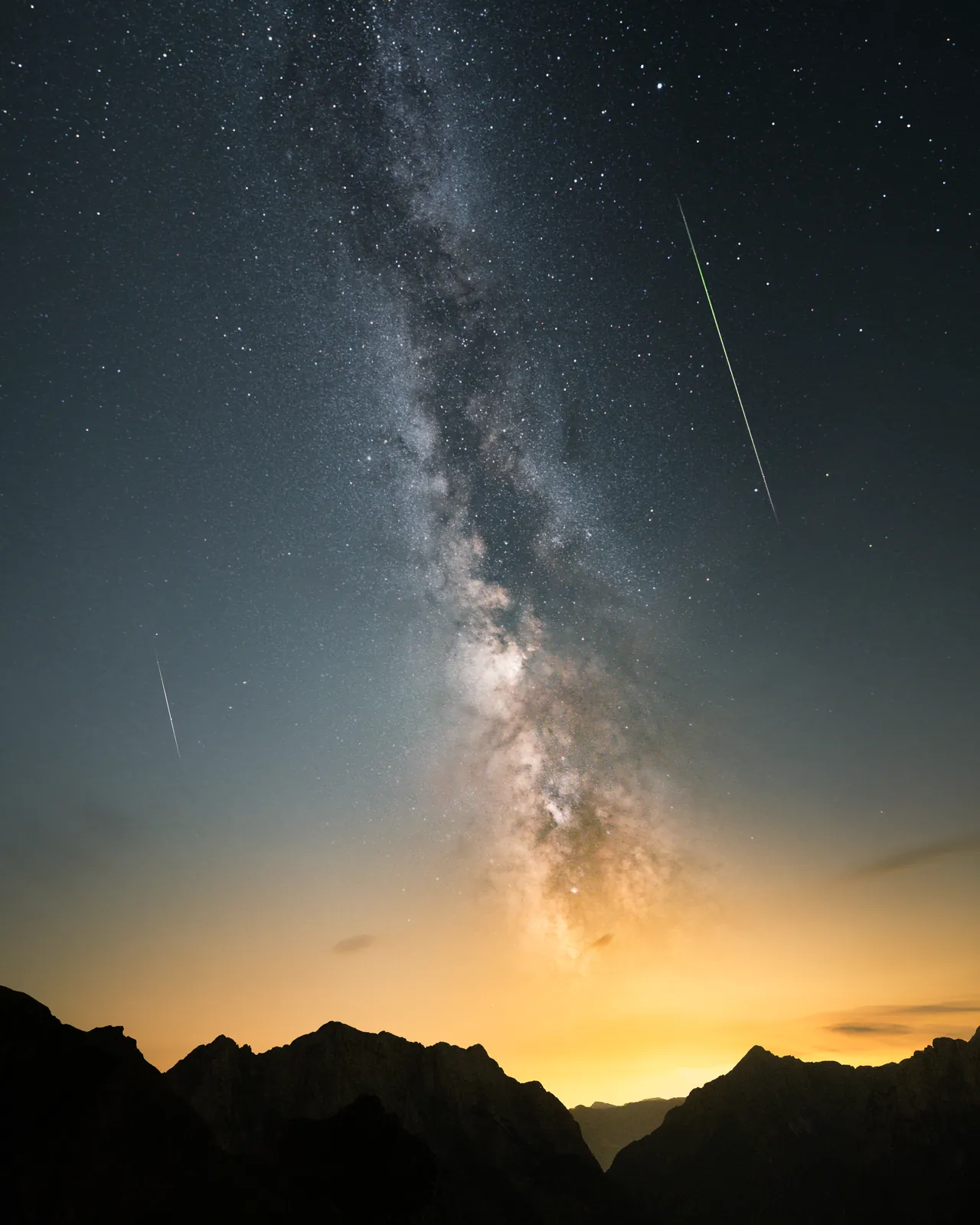 The Milky Way and two meteors over a mountain ridge at dusk